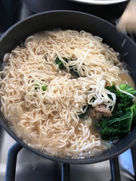 Adding noodles to the broth.