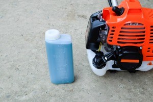 A two-stroke gas next to a trimmer.