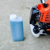 A two-stroke gas next to a trimmer.