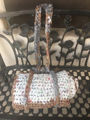 DIY Crochet Plarn Sleeping Mats - finished sleeping mat tied closed and sitting on a wrought iron bench with the handle looped over the back of the bench