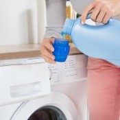 A woman pouring laundry detergent into a measuring cup.