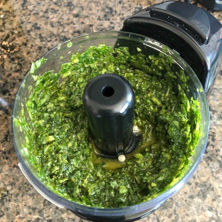 The basil garlic and oil mixture combined in a food processor.