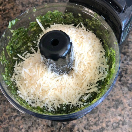 Adding parmesan cheese to the food processor.