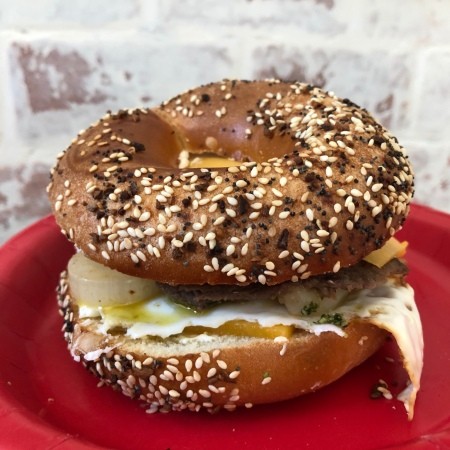 A bagel sandwich topped with basil garlic parmesan sauce.