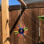Hanging CD Reflective Garden Decoration - multicolored one hanging outside from a 4x4