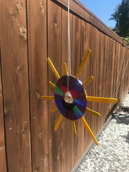 Hanging CD Reflective Garden Decoration - starburst one hanging near a fence