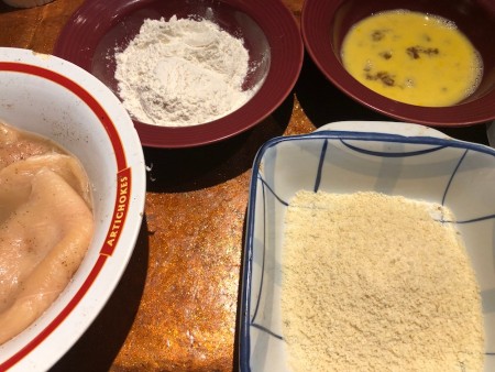 Flour, egg and breading in separate dishes for dredging chicken cutlets.
