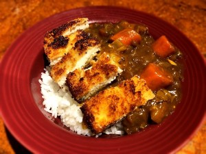 A serving of chicken katsu curry on a plate.