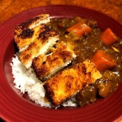 A serving of chicken katsu curry on a plate.