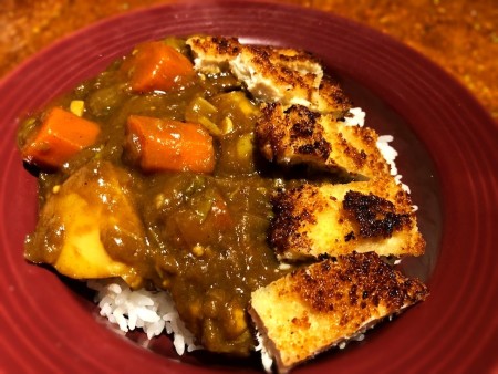 A serving of chicken katsu curry on a plate.