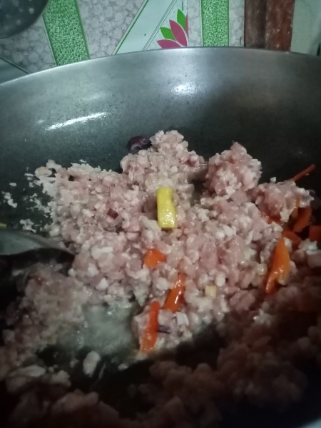 Cooking the ground pork in a frying pan.