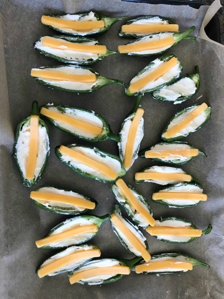 Jalapeño poppers topped with cheddar cheese.