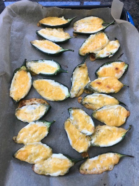 Baked jalapeño poppers on a cookie sheet.