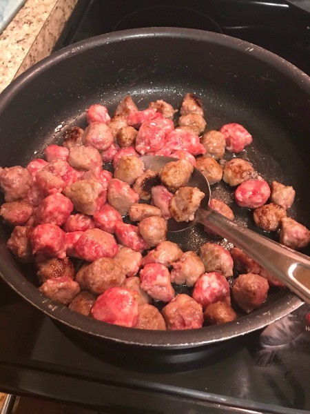 Cooking pieces of sausage in a frying pan.