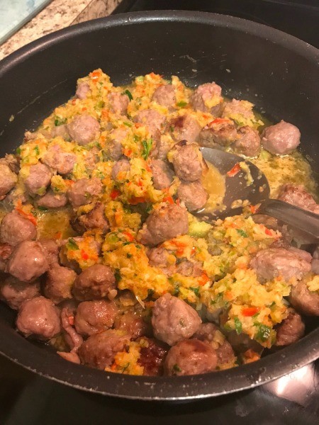 Adding the minced vegetables to the sausage.