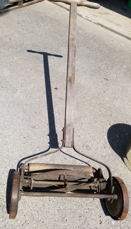 A old reel mower on a concrete surface.