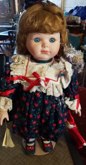 A porcelain baby doll with reddish hair and blue eyes.