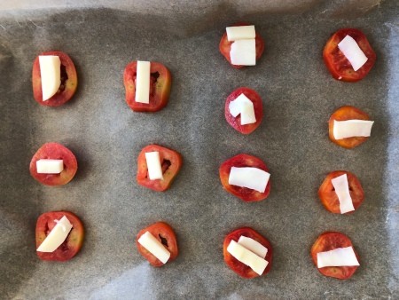Halved tomatoes topped with slices of mozzarella.