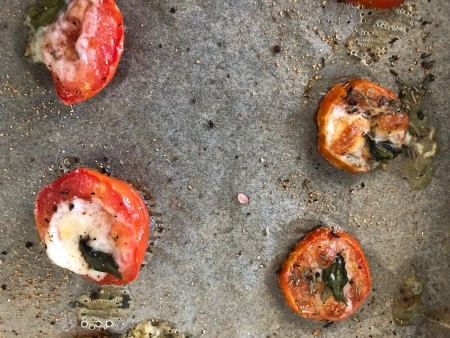 A sheet of baked tomatoes with mozzarella.