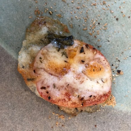 A baked tomato on a cookie sheet.