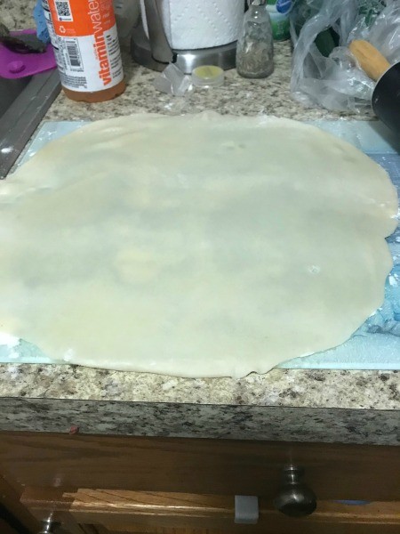 Flattened pie crust on parchment paper.
