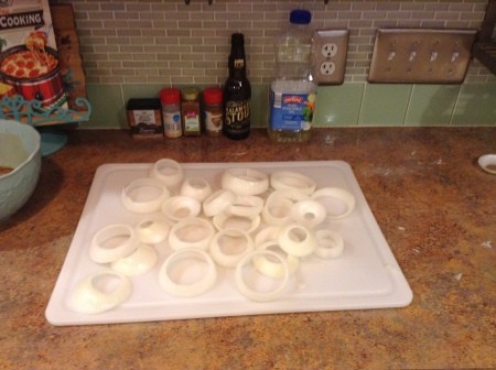 A cutting board full of cut onion rings.