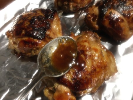 Spooning marinade over the cooked chicken.