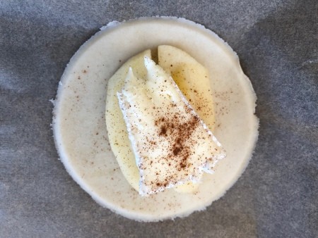Apple and brie on top of a circle of pie dough.