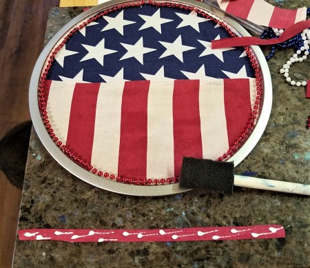 Pizza Pan Flag Wall Hanging - red bead string cut to glue around the inner edge and strip of red fabric cut to glue over the center fabric edges