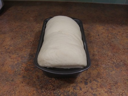 The raised unbaked dough in a bread pan.