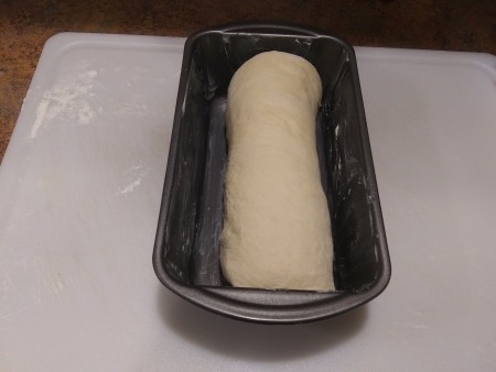 Placing the loaf in a greased bread pan.