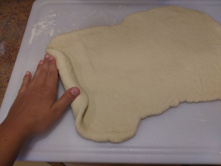 Rolling the bread dough into a loaf.