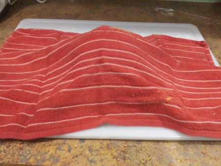 Covering the ball of dough with a towel.