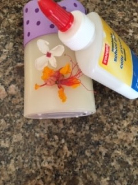 Gluing souvenirs to a white candle.