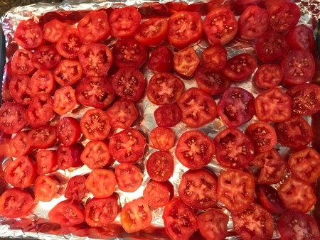 A cookie sheet of tomato slices.