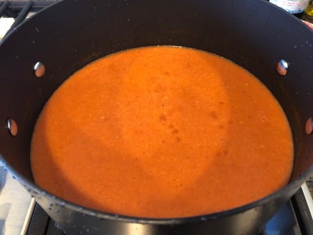 Adding the blended soup back to the pan.
