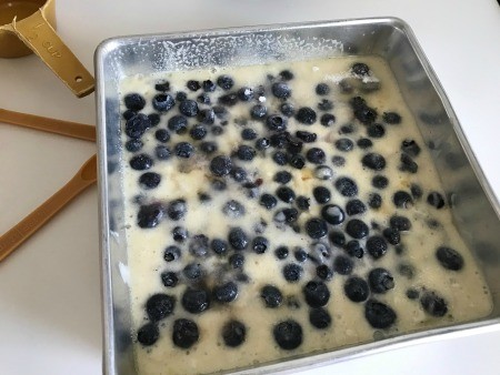 Adding sugar to the top of the cobbler batter.