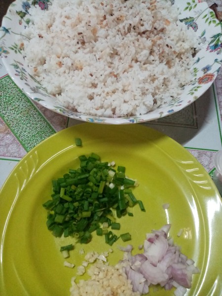 A bowl of cooked rice next to chopped veggies.