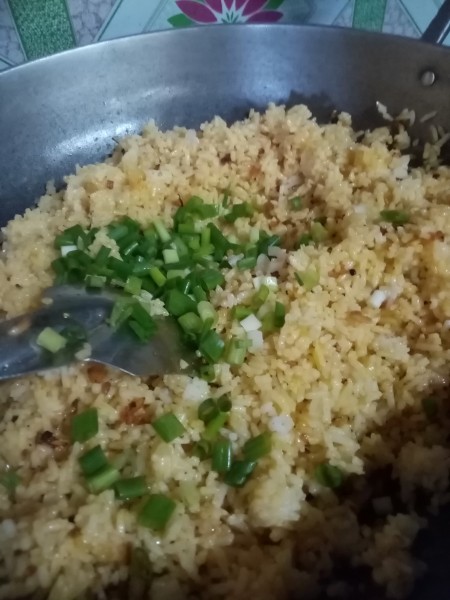 Adding spring onions to the rice mixture.