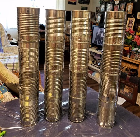 Four stacks of cans for constructing the shelf.