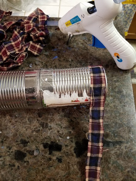 Glueing ribbon to the bottom of the cans.