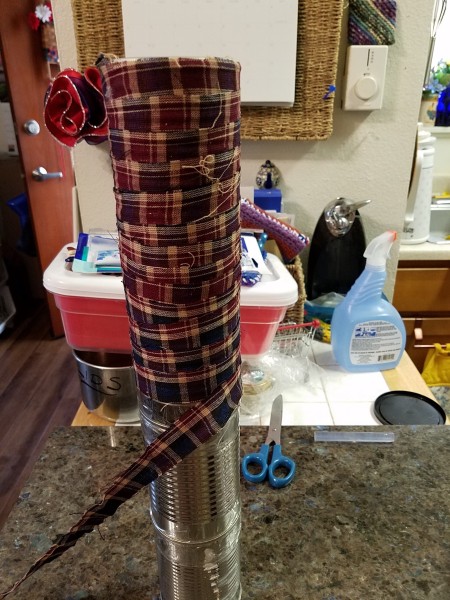 Wrapping ribbon around the tall can structure.