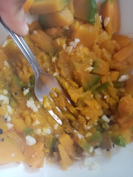 Smashing the cooked squash with a fork.