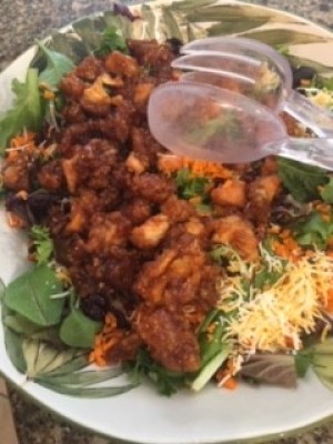 Adding the chicken mixture on top of salad greens.