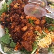 Adding the chicken mixture on top of salad greens.