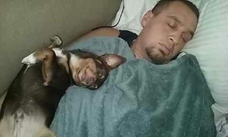 A small dog sleeping with a man.