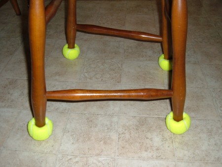 Chair legs with yellow tennis balls on the bottom.