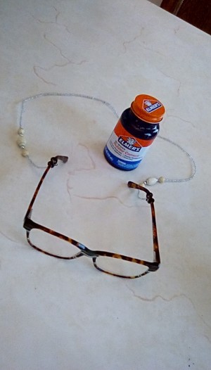 A pair of glasses attached to a neck chain with rubber cement.