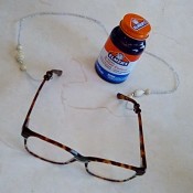 A pair of glasses attached to a neck chain with rubber cement.