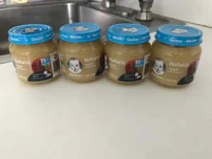 Four jars of baby food on a counter.